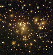 Vzdálená na prach bohatá galaxie A1689-zD1 ležící za kupou galaxií Abell 1689 (popiska)