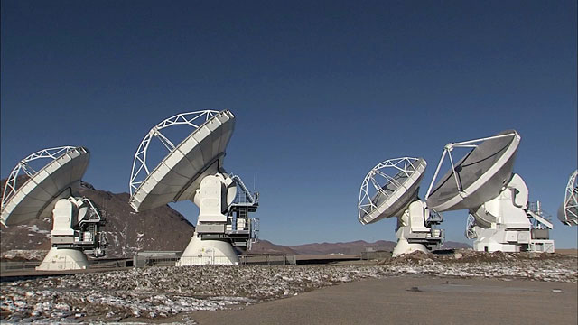 Pan over ALMA array of antennas on Chajnantor as they move in unison